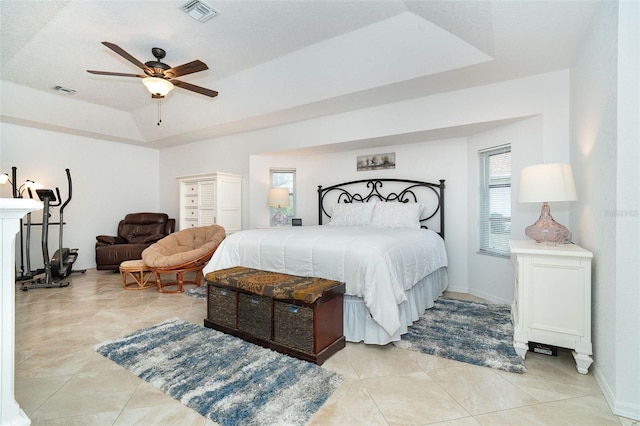 tiled bedroom with ceiling fan and a raised ceiling