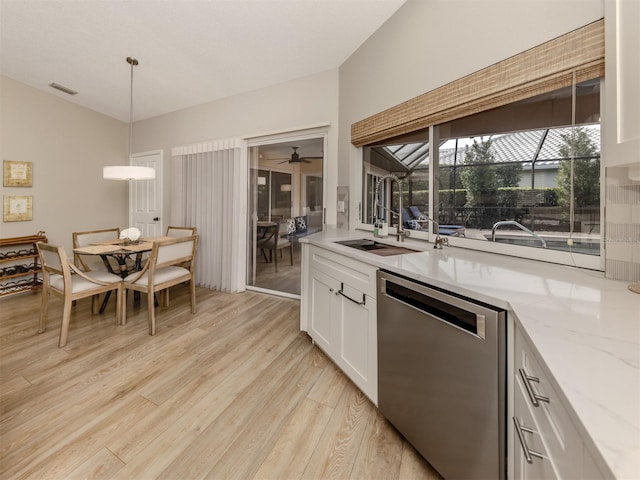 kitchen with hanging light fixtures, stainless steel dishwasher, white cabinets, light wood-type flooring, and light stone counters