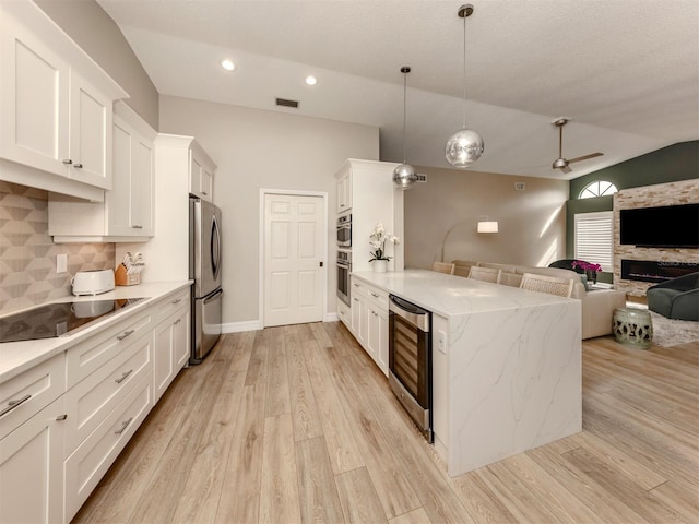 kitchen with white cabinets, pendant lighting, vaulted ceiling, and appliances with stainless steel finishes