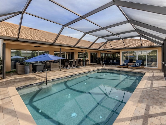 view of swimming pool with glass enclosure, a patio area, and ceiling fan