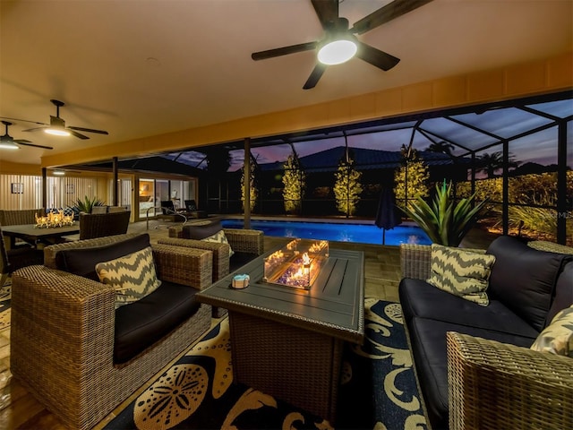 patio terrace at dusk featuring an outdoor living space, ceiling fan, and glass enclosure