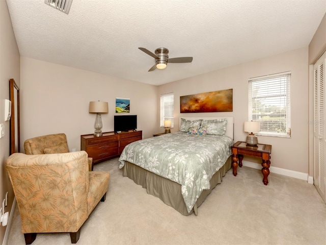 carpeted bedroom with a closet, ceiling fan, and a textured ceiling