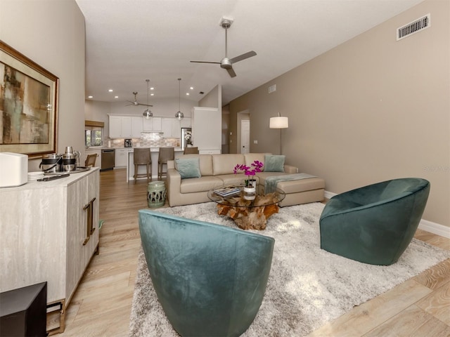 living area featuring a ceiling fan, light wood-style flooring, lofted ceiling, visible vents, and recessed lighting