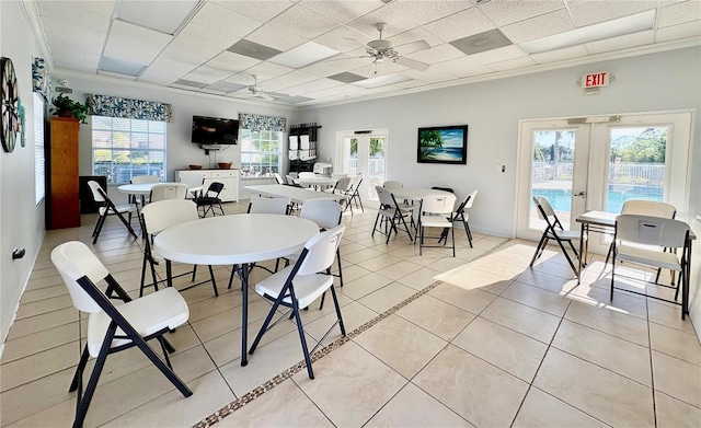 tiled dining space featuring french doors, a paneled ceiling, ornamental molding, and ceiling fan