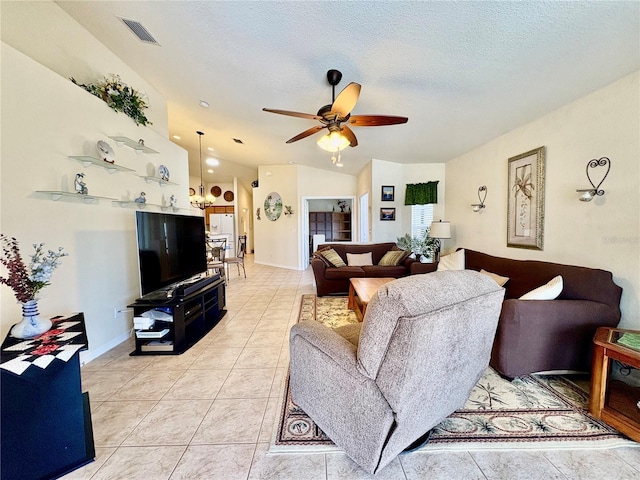 tiled living room with ceiling fan, vaulted ceiling, and a textured ceiling