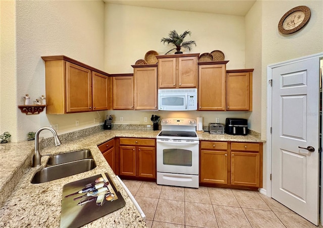 kitchen featuring sink, white appliances, light stone countertops, and light tile patterned floors