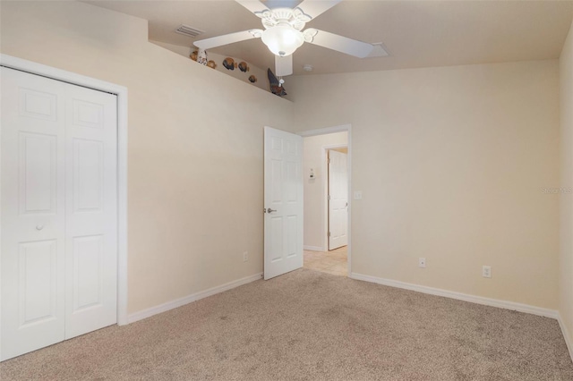 unfurnished bedroom with ceiling fan, light carpet, and a closet