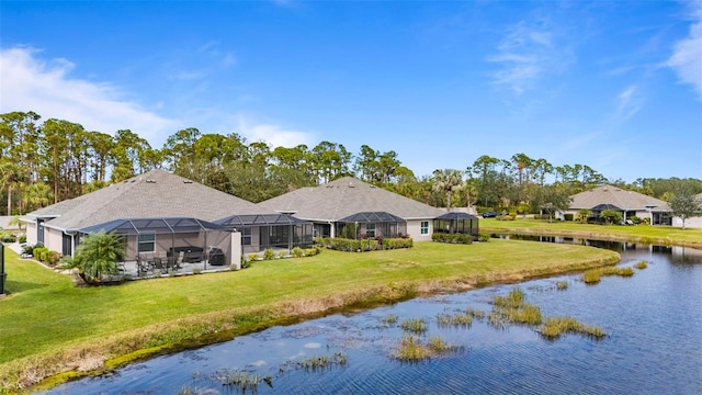 back of property with a water view, a yard, and glass enclosure