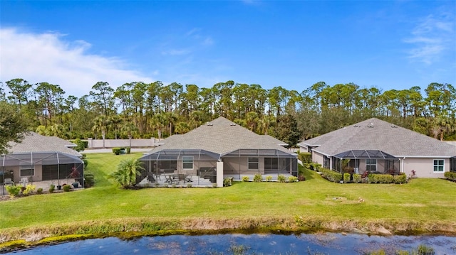 back of property with a water view, a yard, and glass enclosure