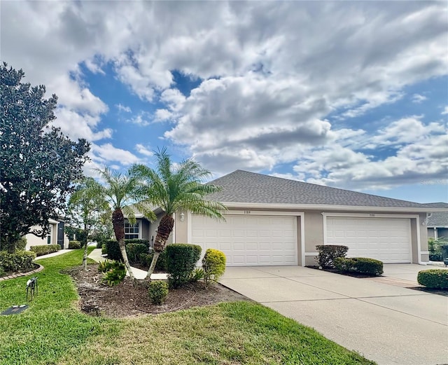 view of front of property with driveway, a front lawn, an attached garage, and stucco siding