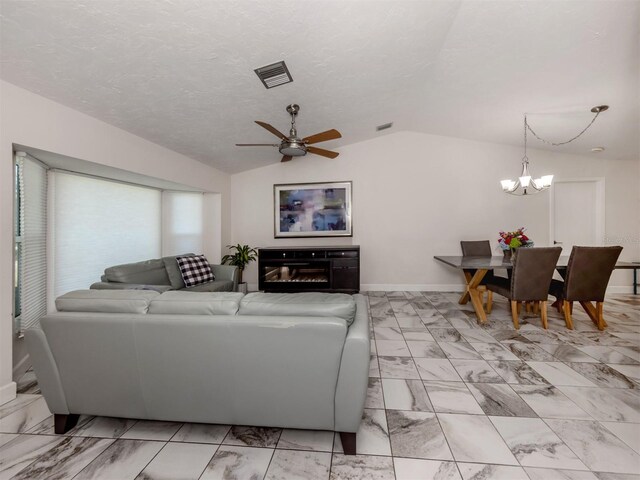 living room featuring lofted ceiling, ceiling fan with notable chandelier, and a textured ceiling