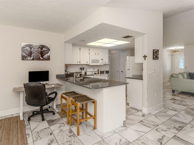 kitchen featuring sink, white cabinetry, dark stone countertops, kitchen peninsula, and white appliances