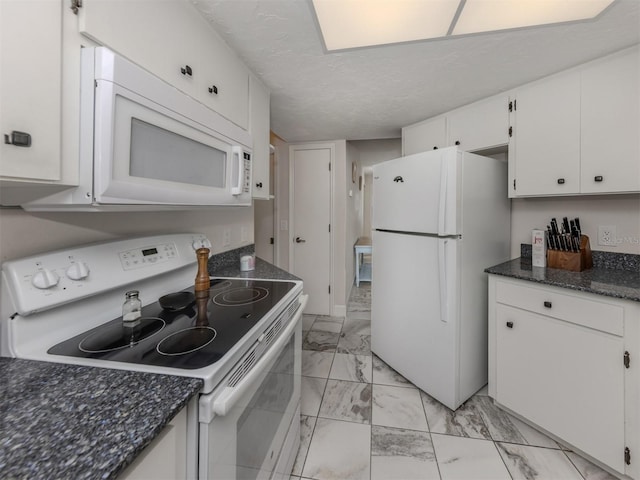 kitchen with a textured ceiling, dark stone countertops, white cabinets, and white appliances