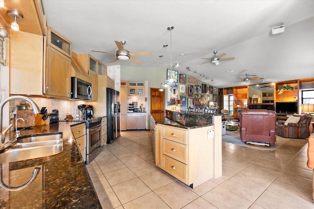 kitchen featuring sink, dark stone countertops, hanging light fixtures, stainless steel appliances, and vaulted ceiling