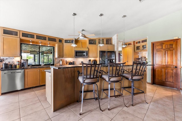 kitchen with stainless steel appliances, a kitchen island, hanging light fixtures, and light tile patterned floors