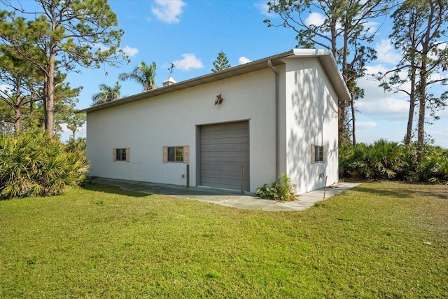 rear view of house with a garage, an outdoor structure, and a yard