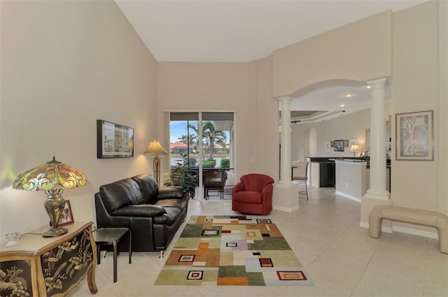 living room featuring light tile patterned floors, a towering ceiling, and ornate columns