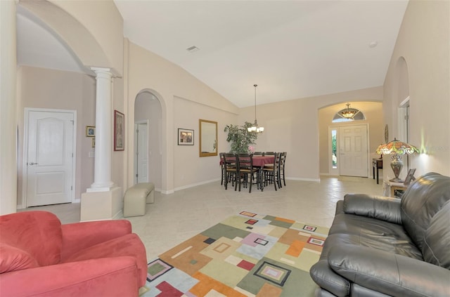 living room featuring light tile patterned floors, a notable chandelier, vaulted ceiling, and ornate columns