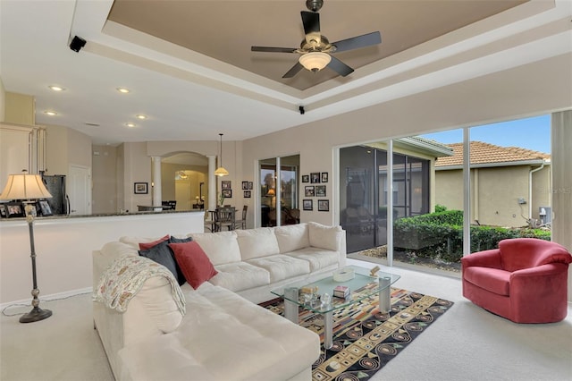 living room with a raised ceiling and ceiling fan