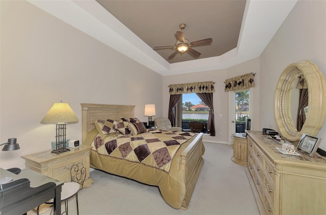 carpeted bedroom featuring a raised ceiling and ceiling fan