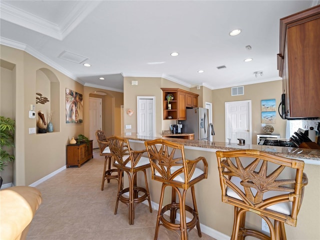 kitchen with a breakfast bar area, stainless steel fridge, light stone counters, and light tile patterned floors