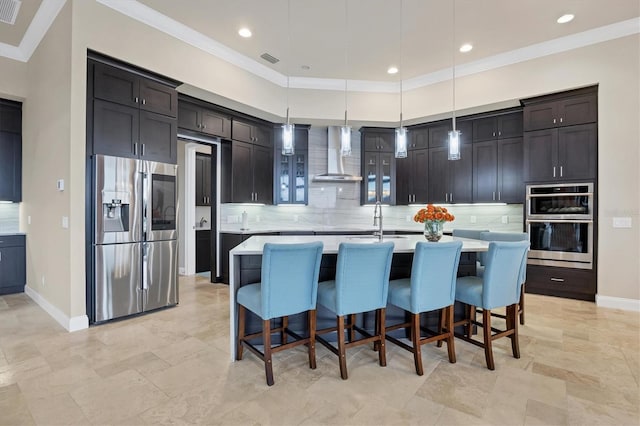 kitchen with stainless steel fridge, hanging light fixtures, a kitchen island with sink, wall chimney range hood, and decorative backsplash