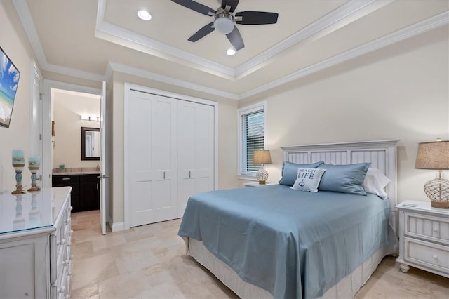 bedroom featuring ceiling fan, ensuite bathroom, a closet, and a tray ceiling