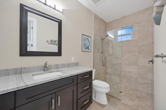 bathroom featuring toilet, vanity, and a tile shower