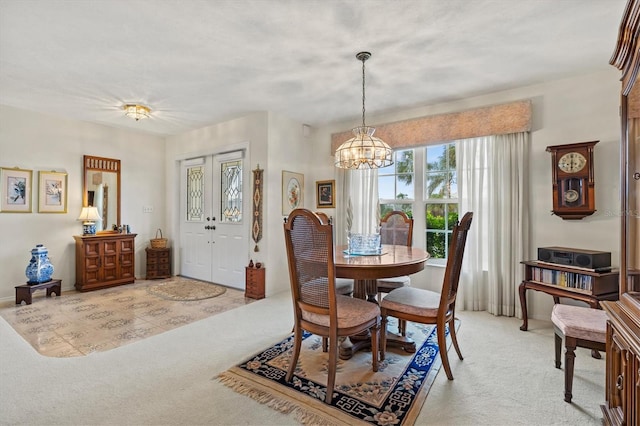 dining room featuring light carpet and a chandelier