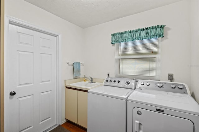 clothes washing area with sink, washing machine and dryer, cabinets, and a textured ceiling