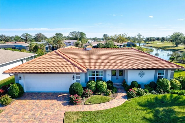 view of front of property featuring a water view, a garage, and a front lawn