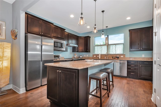 kitchen featuring stainless steel appliances, dark hardwood / wood-style floors, dark brown cabinets, and a kitchen island