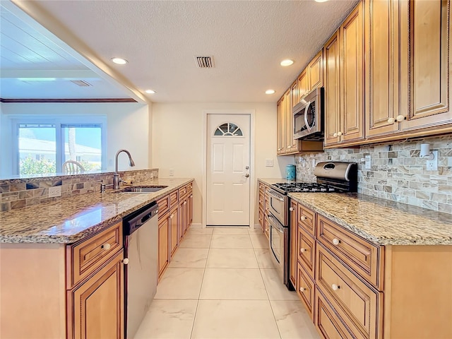 kitchen featuring sink, tasteful backsplash, light stone counters, and appliances with stainless steel finishes