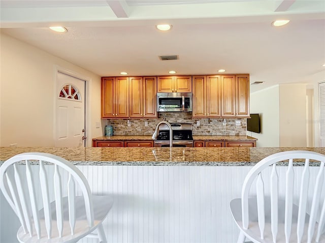 kitchen featuring stainless steel appliances, tasteful backsplash, and light stone countertops