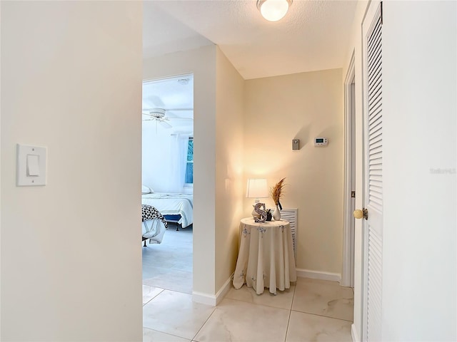 hall featuring a textured ceiling and light tile patterned floors