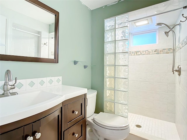 bathroom featuring toilet, a tile shower, and vanity