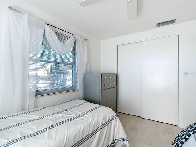 bedroom with ceiling fan, light hardwood / wood-style floors, and a closet