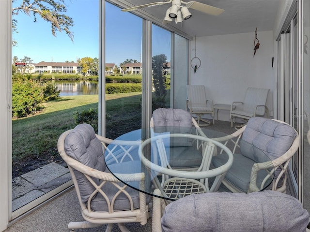 sunroom featuring ceiling fan and a water view