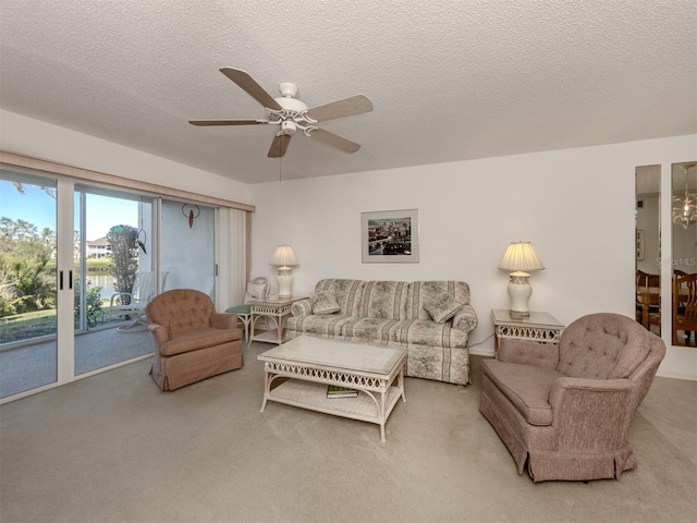 carpeted living room with ceiling fan with notable chandelier and a textured ceiling