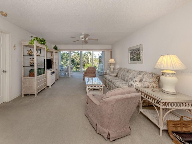 carpeted living room featuring ceiling fan and a textured ceiling