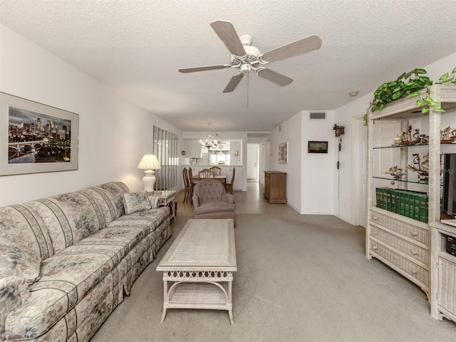 living room featuring ceiling fan with notable chandelier, light carpet, and a textured ceiling