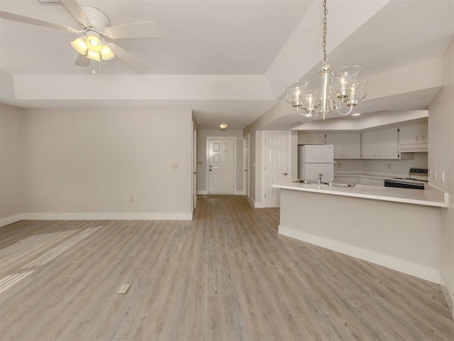 kitchen featuring ceiling fan with notable chandelier, white appliances, a textured ceiling, kitchen peninsula, and light hardwood / wood-style flooring