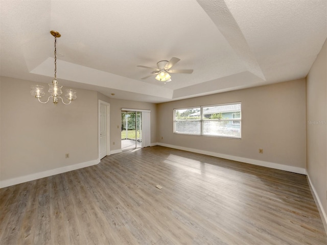 spare room featuring light hardwood / wood-style floors, a textured ceiling, a raised ceiling, and ceiling fan with notable chandelier