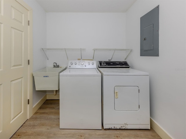 clothes washing area with washer and clothes dryer, sink, electric panel, and light hardwood / wood-style flooring