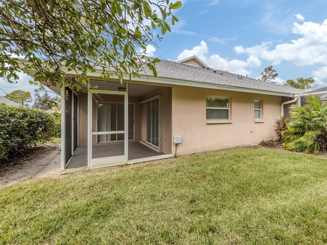 rear view of house featuring a sunroom and a yard