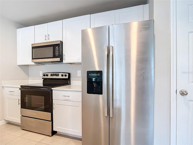 kitchen featuring appliances with stainless steel finishes, light tile patterned floors, and white cabinetry