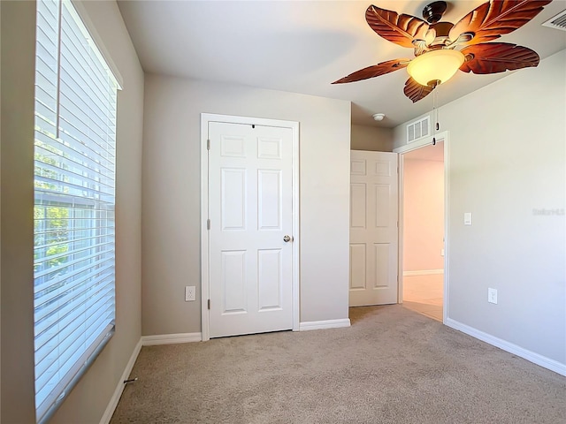 unfurnished bedroom featuring ceiling fan, light colored carpet, and multiple windows