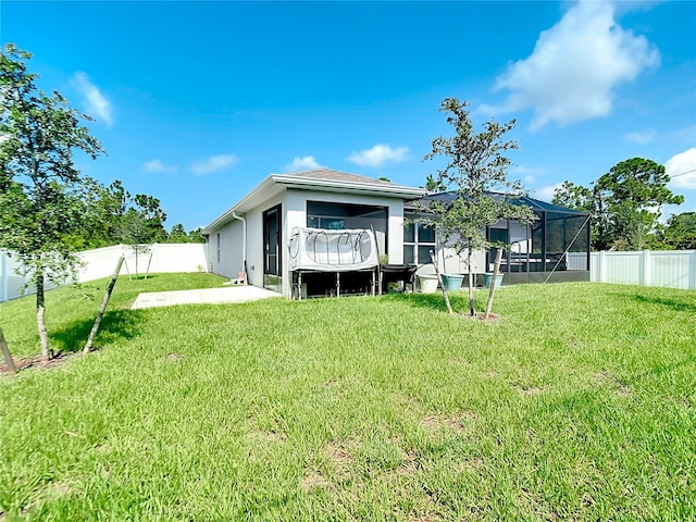 back of house with a yard and glass enclosure