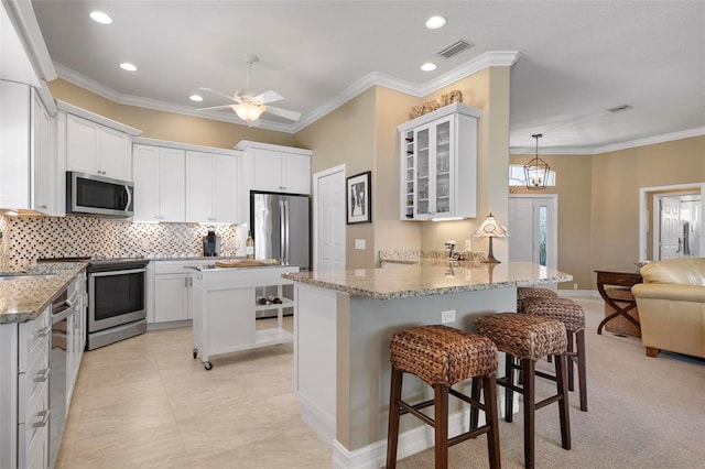 kitchen featuring stainless steel appliances, white cabinets, a kitchen breakfast bar, and kitchen peninsula