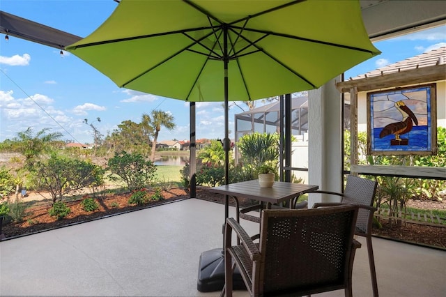 view of patio featuring a water view and glass enclosure